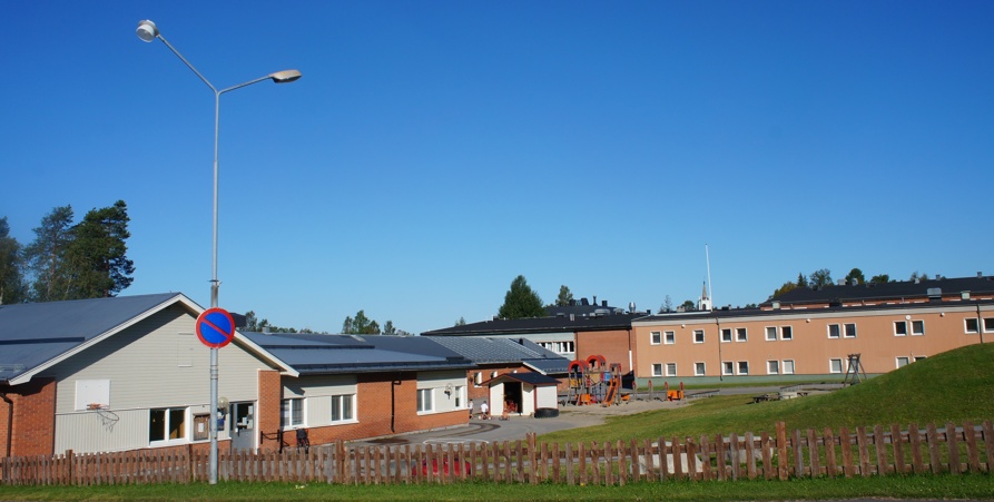 Sommarbild tagen mot barnskolan med lekplats.
